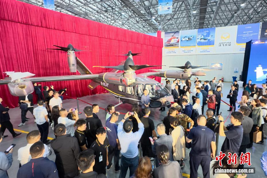 中新社记者 刘忠俊 摄 9月29日，面向低空出行的大型载人eVTOL（电动垂直起降飞行器）AE200-100首架机在四川成都正式下线。这标志着AE200-100首架机已完成机体大部段对接与核心机载系统安装工作，正式迈入适航取证冲刺与量产机型预生产阶段。图为嘉宾近距离观看或拍摄下线的电动垂直起降飞行器AE200-100首架机。