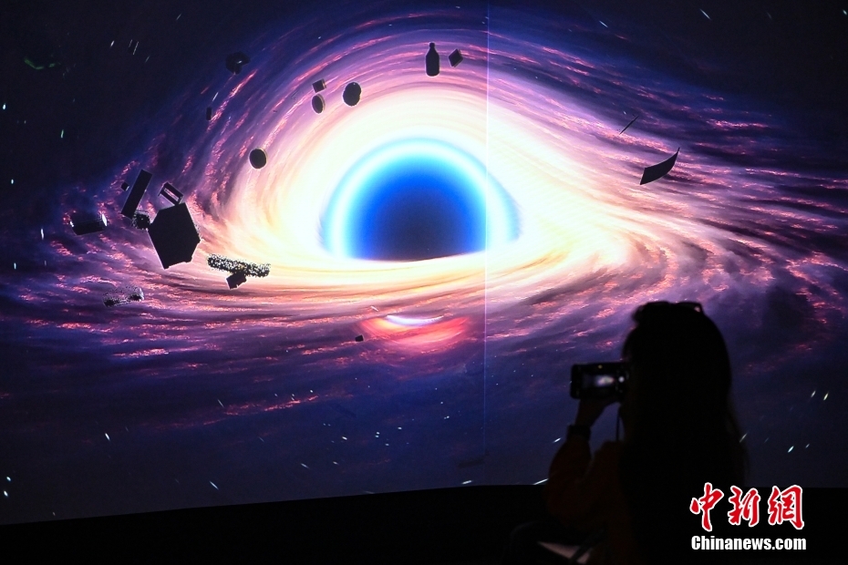 7月2日，由中国国家博物馆、瑞士驻华大使馆、瑞士洛桑联邦理工学院主办，清华大学天文系、清华大学美术学院协办的“宇宙考古：时空探索”展览在北京中国国家博物馆开展。展览分为“仪器和技术：绘制宇宙”“大数据的星空”“可持续的太空”“未来：行星之旅”四个部分，融科学探索和艺术诠释为一体，将宇宙中真实、分散、抽象的数据，通过数字装置、互动体验、动态雕塑和前瞻性设计等多种形式呈现出来。图为参观者在拍摄三屏幕3D数字渲染影像《寒武纪》。 中新社记者 田雨昊 摄