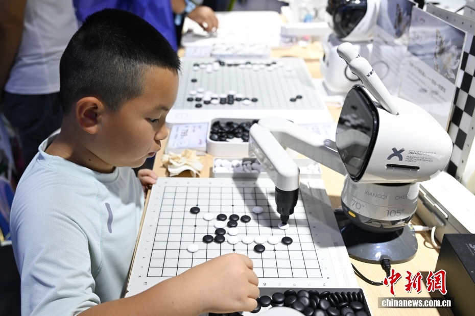 7月26日，小朋友与围棋机器人对弈。当日，2025世界人工智能大会在上海开幕。大会展览面积首次突破7万平方米，吸引了800余家企业参展，集中展示3000余项前沿展品及100余款“全球首发”“中国首秀”新品，规模创历届之最。 中新社记者 汤彦俊 摄