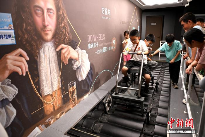 图为小朋友体验方轮车科普游戏。中新社记者 吕明 摄