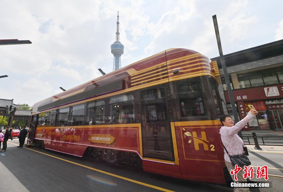 中新社记者 张瑶 摄 6月4日，吉林长春，市民在氢能源文旅专列旁拍照。该专列由中车长客研制，以历史文化街区新民大街建筑群为设计灵感，车内君子兰花海主题内饰与复古留声机相映成趣。列车采用三级安全防护氢能系统，单次加氢续航320公里。