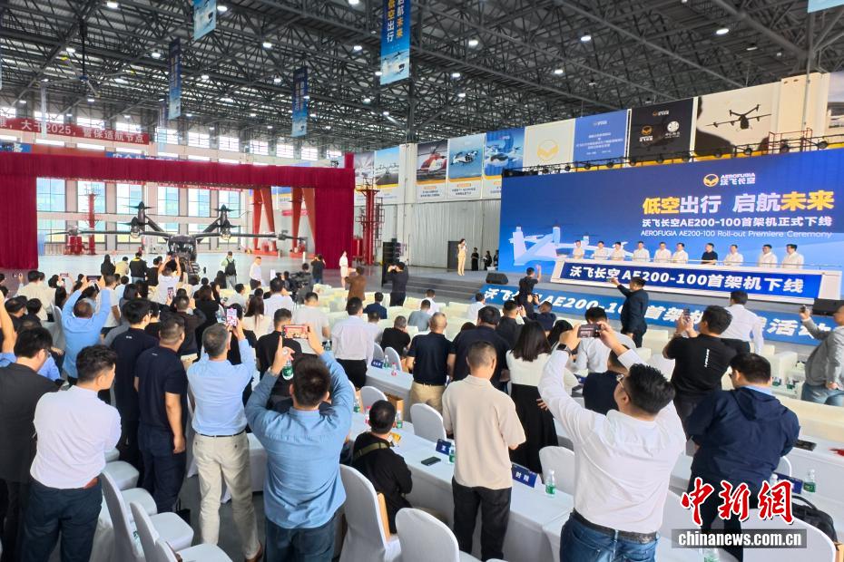 中新社记者 刘忠俊 摄 9月29日，面向低空出行的大型载人eVTOL（电动垂直起降飞行器）AE200-100首架机在四川成都正式下线。这标志着AE200-100首架机已完成机体大部段对接与核心机载系统安装工作，正式迈入适航取证冲刺与量产机型预生产阶段。图为嘉宾共同启动大幕，电动垂直起降飞行器AE200-100首架机揭开面纱。