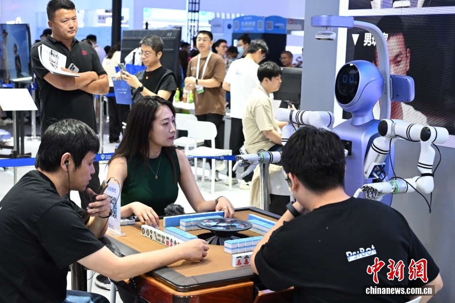 7月26日，参观者和工作人员与人形机器人一起打麻将。当日，2025世界人工智能大会在上海开幕。大会展览面积首次突破7万平方米，吸引了800余家企业参展，集中展示3000余项前沿展品及100余款“全球首发”“中国首秀”新品，规模创历届之最。 中新社记者 汤彦俊 摄