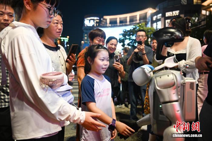 8月19日，人形机器人和街头行人握手。中新社记者 王刚 摄
