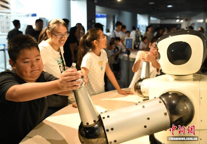 8月21日，正值暑假，重庆科技馆变身儿童乐园，吸引不少市民带着小孩前来参观、游玩，探索科学奥秘。图为小朋友与测力机器人扳手劲比力气。中新社记者 周毅 摄