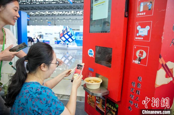 图为参观者拍摄由“AI智能螺蛳粉售卖机”制作的螺蛳粉。中新社记者 陈冠言 摄