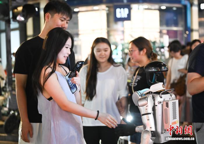 8月19日，街头行人和人形机器人握手。中新社记者 王刚 摄