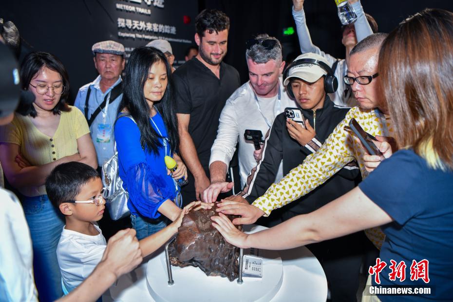 中新社记者 骆云飞 摄 6月10日，中外游客用手触摸展出的西北非铁陨石。当日，海南文昌极星陨石博物馆内游客络绎不绝。该博物馆以“陨石科学+航天探索”为主题，展出400余件珍贵陨石标本，通过陨石标本展示、陨石演化场景及前沿科技手段，让游客近距离感受陨石的奥秘与宇宙的浩瀚。