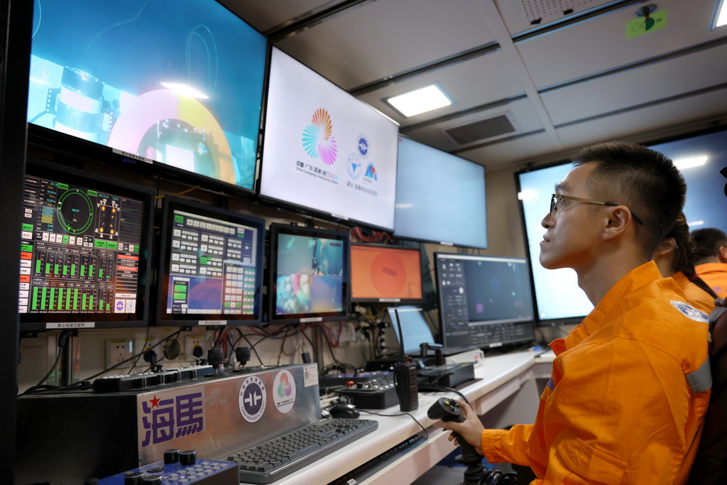 在科考船上的“海马”号深海遥控潜水器控制室里，工作人员遥控采火装置在海底进行作业（9月18日摄）。 10月9日，第十五届全国运动会、全国第十二届残疾人运动会暨第九届特殊奥林匹克运动会火种采集仪式在广州举行。全运圣火“源火”来自南海1500多米深海底，通过引燃可燃冰的方式获取。 9月18日，在南海北部海域，我国自主研发的“海马”号深海遥控潜水器（ROV）搭载“可燃冰原位采集分解及引燃装置”下潜到1500多米深海底，科研人员远程操控采集可燃冰，并降压使其分解，产生的甲烷气体即为“源火”气源。随后，科考船甲板面的太阳能光伏装置发电并传输到海底，引燃气源获取“源火”。“海马”号携带燃烧的“源火”返回科考船甲板面后，科研人员将“源火”转移至“源火”盒，“源火”采集成功。新华社记者 卢汉欣 摄