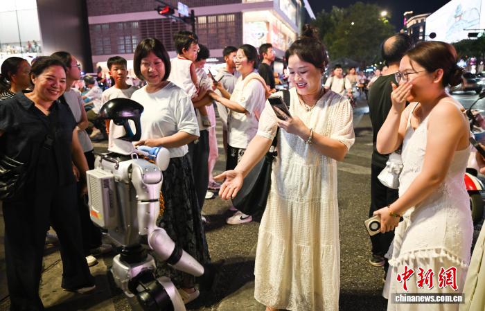8月19日，人形机器人吸引行人观看。中新社记者 王刚 摄