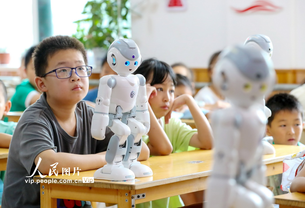 8月4日，在山东青岛莱西市河头店镇龙泉湖新村小雨滴暑假公益课堂，返乡大学生和青年志愿者为村里小朋友们带来一堂别开生面的机器人科普课。通过讲解原理与未来应用、模型展示及机器人、机器狗表演，让小朋友们零距离体验科技魅力，点燃创新梦想。张进刚摄（人民图片网）