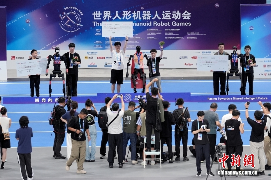 中新社记者 张祥毅 摄 8月17日，2025世界人形机器人运动会100米决赛在北京国家速滑馆（冰丝带）举行，以AI自主操控的天工机器人以21秒50的成绩获本次比赛冠军，灵翌科技和高羿科技以22秒08和24秒53的成绩分获亚军和季军。图为颁奖仪式。