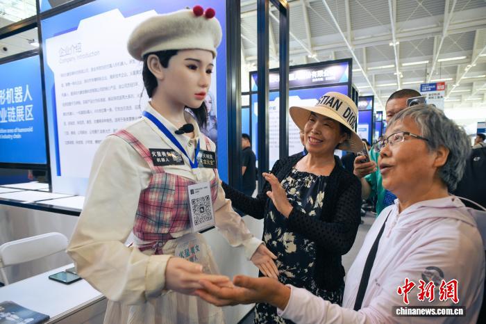 图为人形机器人与参观者互动。中新社记者 佟郁 摄