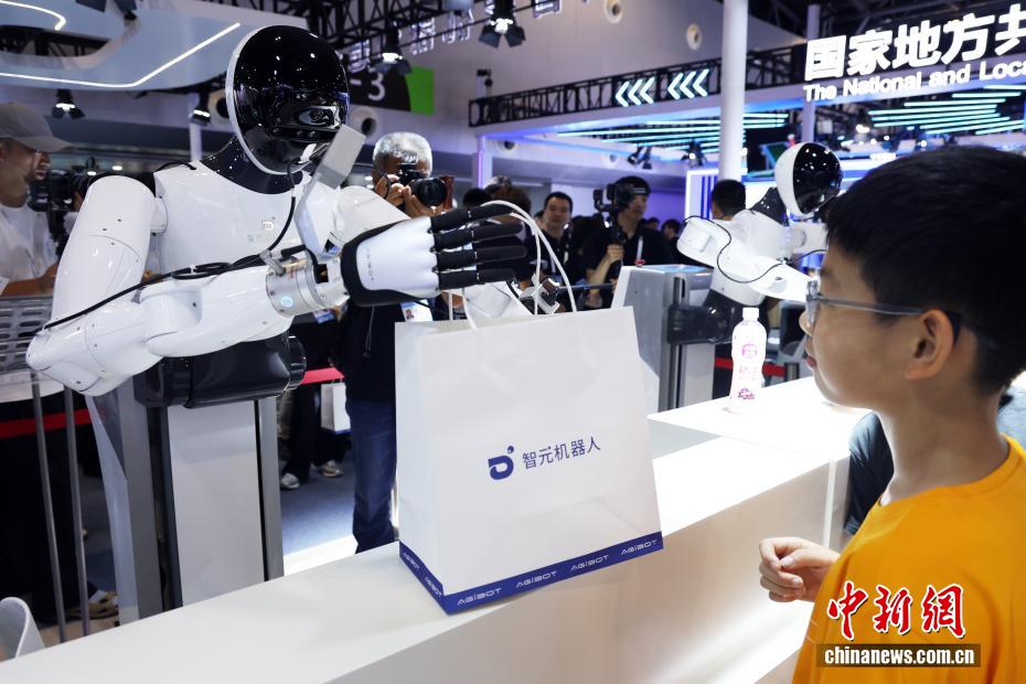 7月26日，机器人在分发纪念品。当日，2025世界人工智能大会在上海开幕。今年大会展览面积首次突破7万平方米，吸引了800余家企业参展，集中展示3000余项前沿展品及100余款