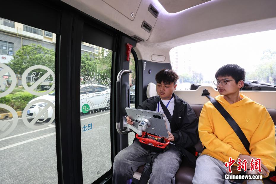 中新社记者 瞿宏伦 摄 5月4日，安全员在监控无人驾驶巴士运行状态吸引乘客观看。为了确保运行安全，专线在运营中采用了人机协同模式，安排了一名安全员随时监控巴士运行状态。当日，贵州首条无人驾驶公交线——“无人驾驶花溪大学城专线”在贵州省贵安新区开通运营。该专线使用的无人驾驶巴士核载6人，具备L4级自动驾驶能力，能为乘客提供3-10公里的无人接驳服务。专线主要基于公交运营模式，单向全程为5公里，通勤时长为15分钟至20分钟，5月4日至31日实行免费体验，乘客可通过扫描站牌二维码或线上预约乘坐。