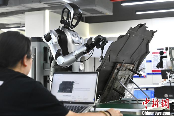 图为人形机器人正在进行汽车零部件装配训练。中新社记者 韩苏原 摄