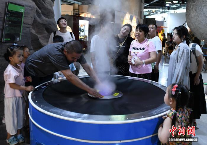8月21日，正值暑假，重庆科技馆变身儿童乐园，吸引不少市民带着小孩前来参观、游玩，探索科学奥秘。图为市民与小孩一起探索云团的奥秘。中新社记者 周毅 摄