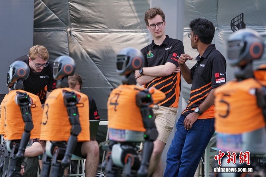 8月13日，在北京国家速滑馆的人形机器人赛训基地，来自荷兰埃因霍芬理工大学的参赛队员在交流中。8月14日至17日，2025世界人形机器人运动会将在北京国家速滑馆（冰丝带）举行。来自全球五大洲16个国家的280支队伍、500余台人形机器人将展开26个赛项、538个比赛项目的竞技对决。中新社记者 张祥毅 摄