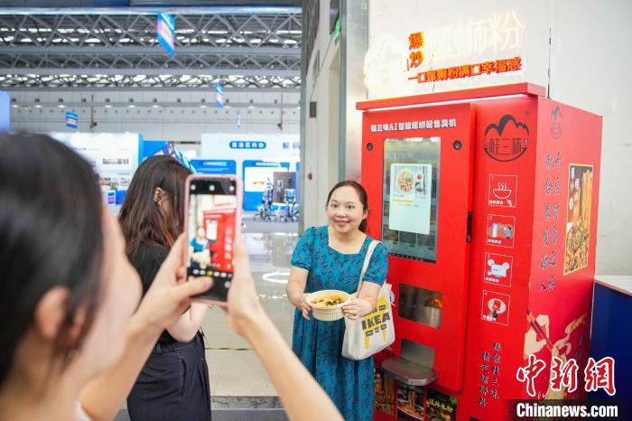 图为参观者手持由“AI智能螺蛳粉售卖机”制作的螺蛳粉拍照。中新社记者 陈冠言 摄