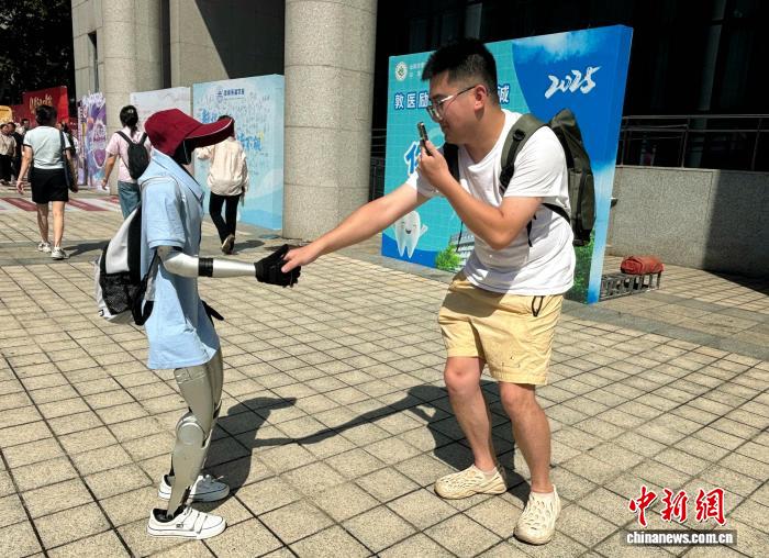 学生与人形机器人握手互动。高艺芯 摄