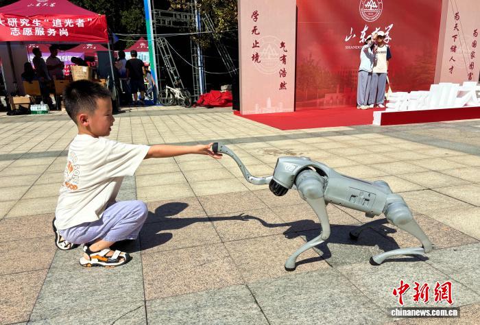 小朋友和机器狗握手互动。高艺芯 摄