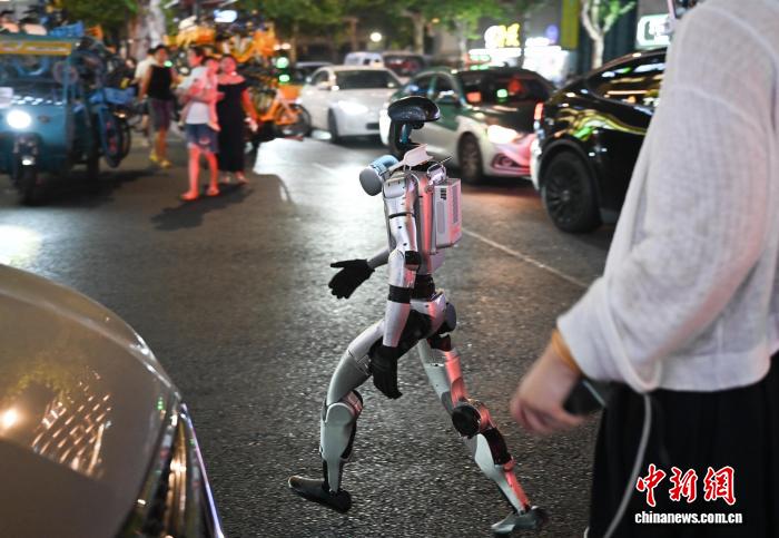 8月19日，人形机器人在街头避开车辆。中新社记者 王刚 摄