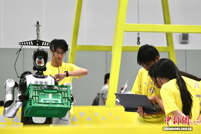 8月24日，第二十七届中国机器人及人工智能大赛人形机器人专项赛全国决赛在安徽省合肥市开赛，该赛事也是中国首个全尺寸人形机器人赛事。比赛吸引了中国近400所高校的6000余名学生参与。赛题紧密围绕工业、家庭服务等真实场景需求，推动人形机器人在多场景中的技术验证与应用突破。图为全尺寸人形机器人正在进行搬运比赛。中新社记者 韩苏原 摄