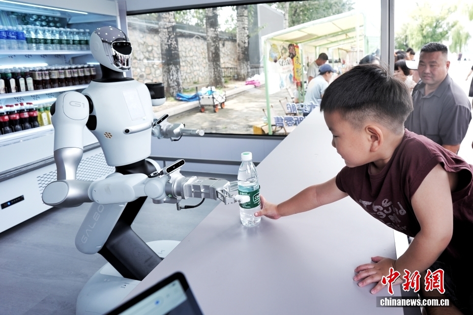 中新社记者 张祥毅 摄 9月13日，在北京颐和园的一家机器人零售店，机器人向小朋友交付商品。据了解，该零售店由机器人自主提供接待、点单、支付、取货、交付全流程服务，主营饮料和公园文创产品。