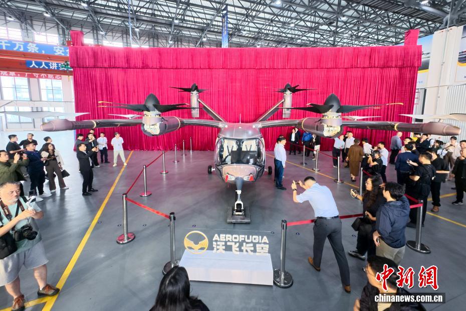 中新社记者 刘忠俊 摄 9月29日，面向低空出行的大型载人eVTOL（电动垂直起降飞行器）AE200-100首架机在四川成都正式下线。这标志着AE200-100首架机已完成机体大部段对接与核心机载系统安装工作，正式迈入适航取证冲刺与量产机型预生产阶段。图为下线的电动垂直起降飞行器AE200-100吸引嘉宾拍照。