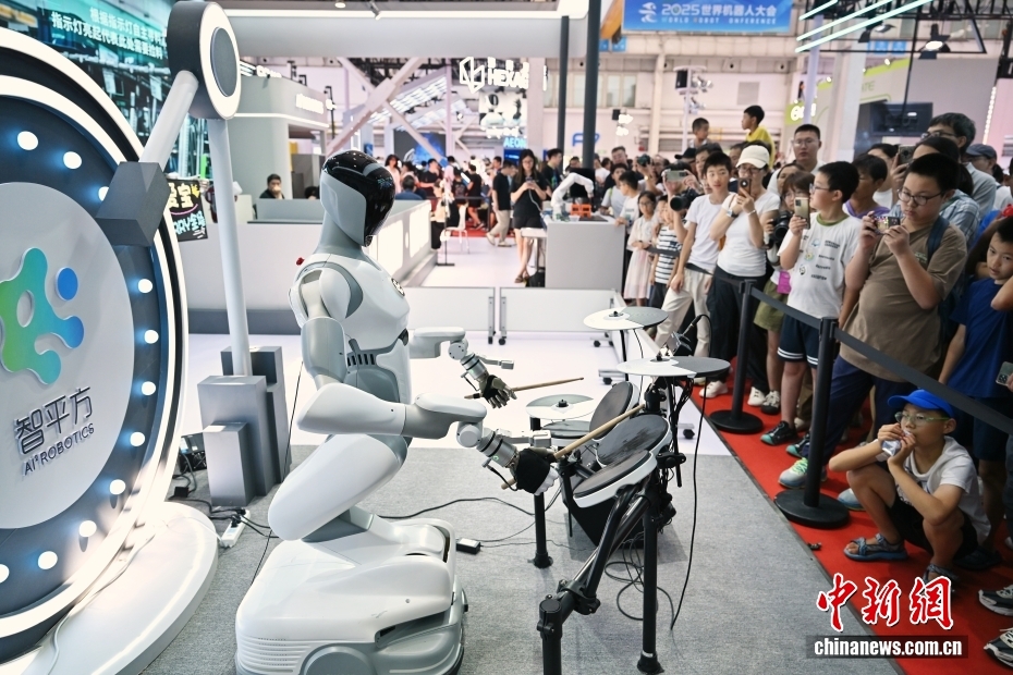 中新社记者 王紫儒 摄 8月10日正值周末，世界机器人大会人气旺。2025世界机器人大会于8月8日至12日在北京亦庄举行，主题为“让机器人更智慧，让具身体更智能”。图为智平方展台的机器人爱宝表演架子鼓。