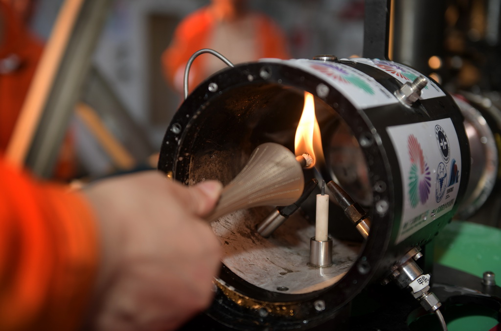 在科考船甲板面，工作人员从搭载在“海马”号深海遥控潜水器上的采火装置里取火（9月18日摄）。 10月9日，第十五届全国运动会、全国第十二届残疾人运动会暨第九届特殊奥林匹克运动会火种采集仪式在广州举行。全运圣火“源火”来自南海1500多米深海底，通过引燃可燃冰的方式获取。 9月18日，在南海北部海域，我国自主研发的“海马”号深海遥控潜水器（ROV）搭载“可燃冰原位采集分解及引燃装置”下潜到1500多米深海底，科研人员远程操控采集可燃冰，并降压使其分解，产生的甲烷气体即为“源火”气源。随后，科考船甲板面的太阳能光伏装置发电并传输到海底，引燃气源获取“源火”。“海马”号携带燃烧的“源火”返回科考船甲板面后，科研人员将“源火”转移至“源火”盒，“源火”采集成功。新华社记者 卢汉欣 摄
