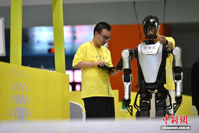 8月24日，第二十七届中国机器人及人工智能大赛人形机器人专项赛全国决赛在安徽省合肥市开赛，该赛事也是中国首个全尺寸人形机器人赛事。比赛吸引了中国近400所高校的6000余名学生参与。赛题紧密围绕工业、家庭服务等真实场景需求，推动人形机器人在多场景中的技术验证与应用突破。图为参赛队员正在调试全尺寸人形机器人。中新社记者 韩苏原 摄