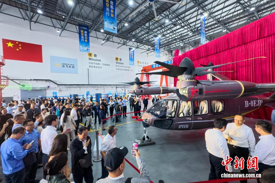 中新社记者 刘忠俊 摄 9月29日，面向低空出行的大型载人eVTOL（电动垂直起降飞行器）AE200-100首架机在四川成都正式下线。这标志着AE200-100首架机已完成机体大部段对接与核心机载系统安装工作，正式迈入适航取证冲刺与量产机型预生产阶段。图为下线的电动垂直起降飞行器AE200-100吸引众人驻足观看。