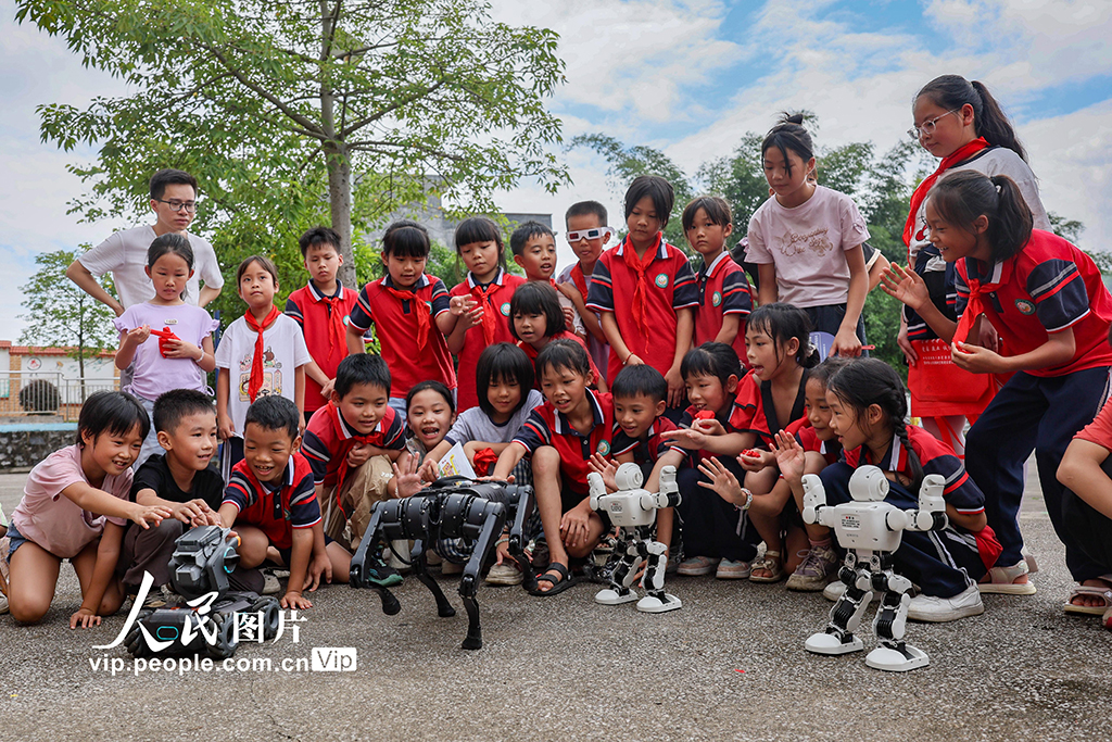 2025年9月11日，在广西贺州市八步区灵峰镇中心学校，学生与机器人、机器狗互动。学校通过科普知识讲解激发学生创新创造意识和科学探索精神，让师生在互动与体验中感受科技的魅力。黎豪图摄（人民图片网）